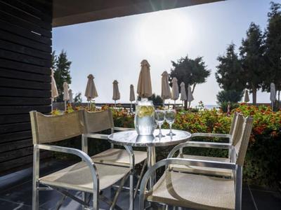 Terrazza con tavolo, sedie e bevande alla luce del sole con ombrelloni sullo sfondo.