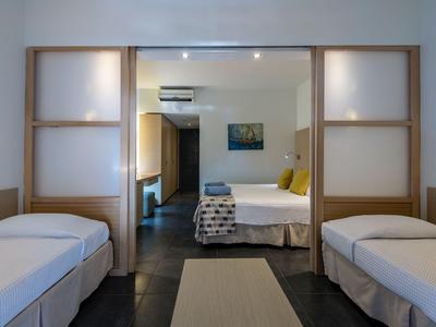 Stanza con due letti singoli, letto matrimoniale adiacente, design moderno e arredi minimalisti.