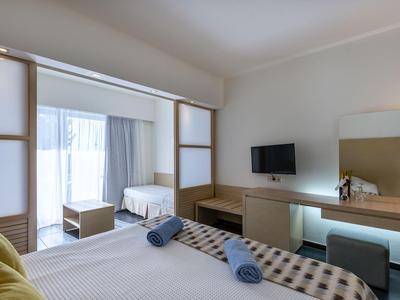 Camera d'hotel moderna con letto matrimoniale, scrivania, TV e grande finestra con tende.