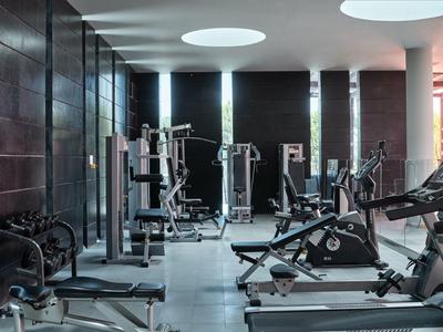 Palestra luminosa con attrezzature moderne e grandi finestre.