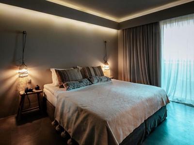 Modern eingerichtetes Schlafzimmer mit großem Bett, beigen Vorhängen und sanfter Beleuchtung.