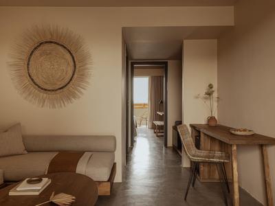 Modern eingerichtetes Hotelzimmer mit Sofa, Schreibtisch und neutralen Farbtönen.
