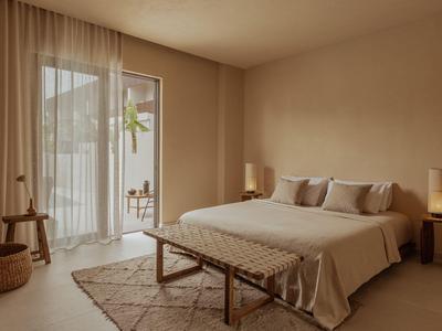 Modern eingerichtetes Schlafzimmer mit großem Bett, Teppich und Zugang zu Balkon.