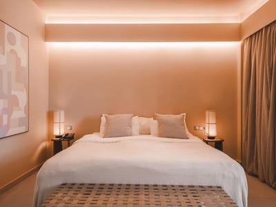 Schlafzimmer mit großem Bett, warmem Licht und moderner Dekoration in neutralen Tönen.