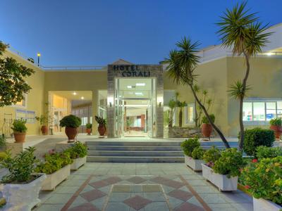 Hotelentree met palmbomen, planten en verlichte gevel bij schemering