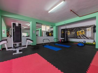 Lichte sportschool met trainingsapparatuur, spiegels en gekleurde gepolsterde vloer.