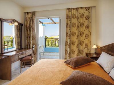 Hell eingerichtetes Schlafzimmer mit Doppelbett, Zugang zu Balkon mit Meerblick.