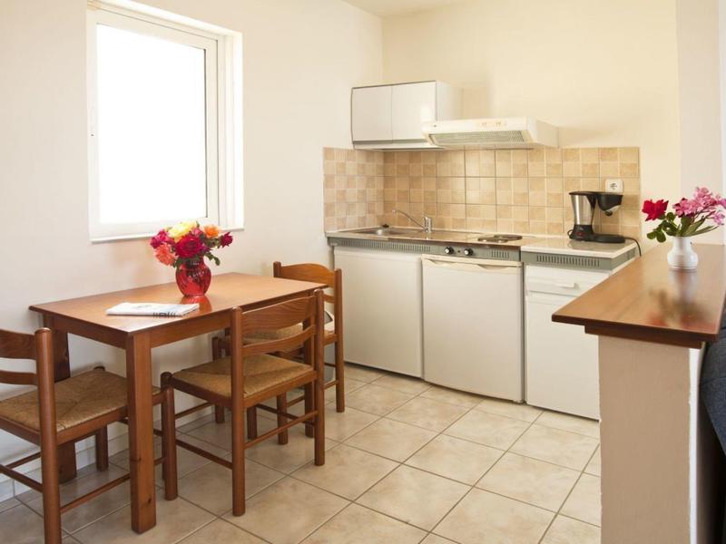 Kleine Küchenzeile mit Tisch und vier Stühlen in einem hellen Raum.