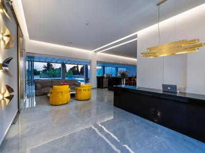 Reception moderna di un hotel con poltrone gialle e bancone nero alla luce del giorno.