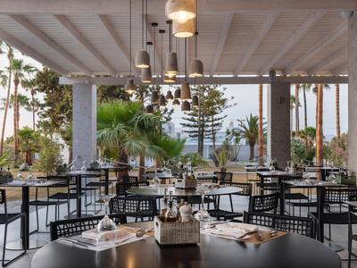 Ristorante all'aperto con mobili neri e vista sul giardino tropicale.