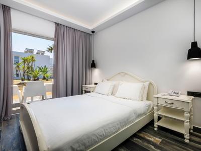 Bright bedroom with double bed, nightstands, and access to terrace with sea view.