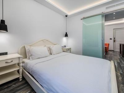 Bedroom with double bed, white walls, two nightstands, and modern pendant lights.