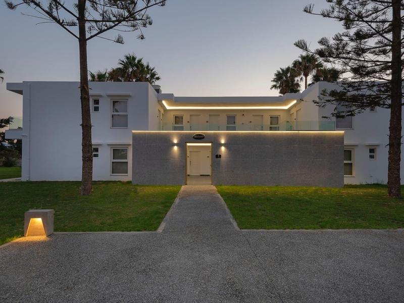 Modern illuminated house with garden and walkway at dusk.