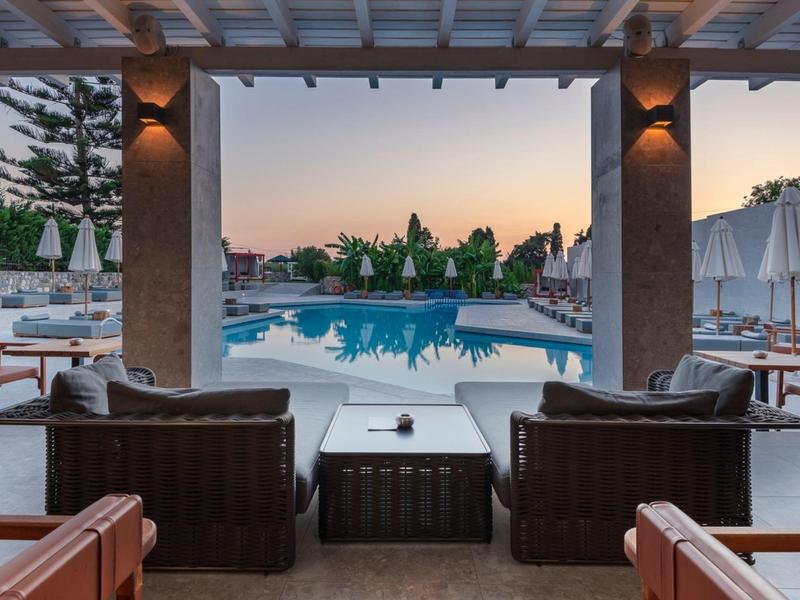 Evening view of a lit pool area with outdoor chairs and tables.
