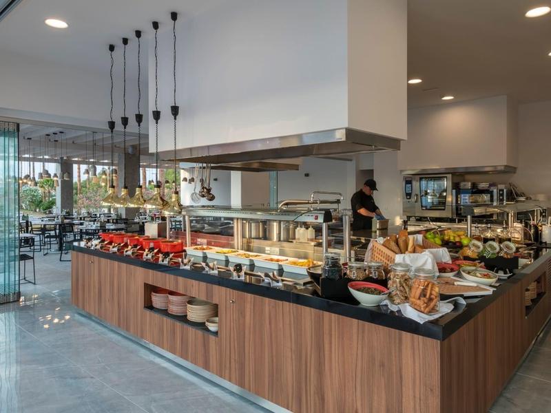 Modern buffet station in a bright restaurant with various dishes and rustic wood design.
