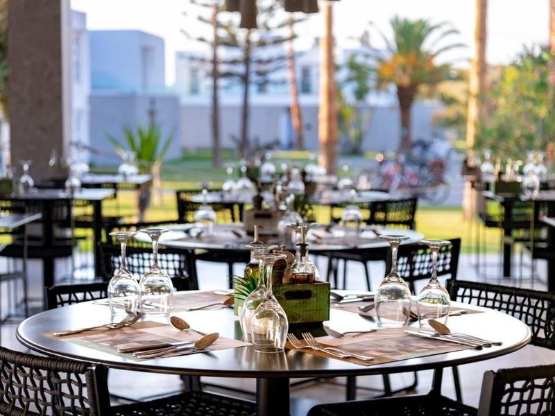 Elegant outdoor restaurant with beautifully set tables and view of palm trees.