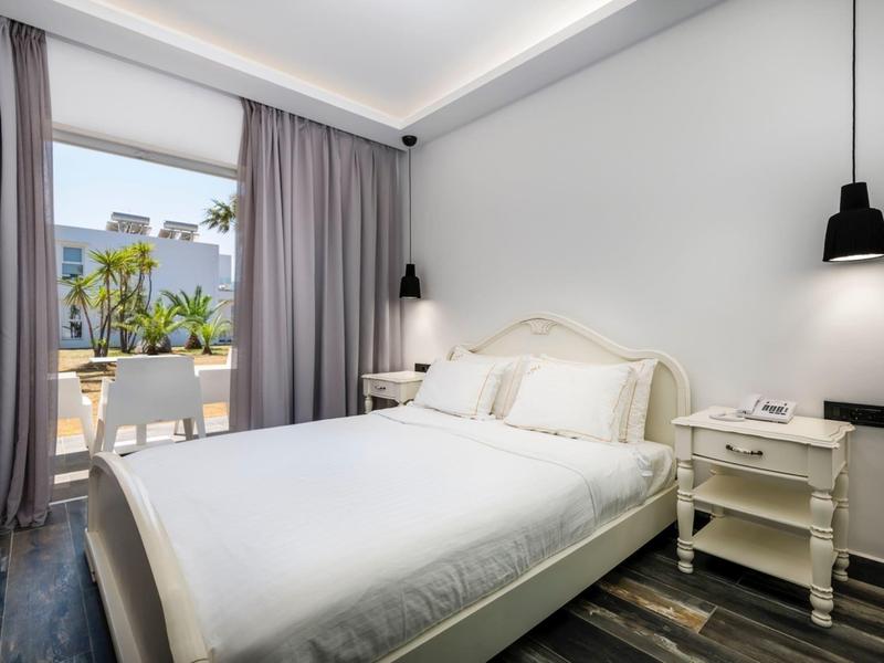 Bright bedroom with double bed, nightstands, and access to terrace with sea view.