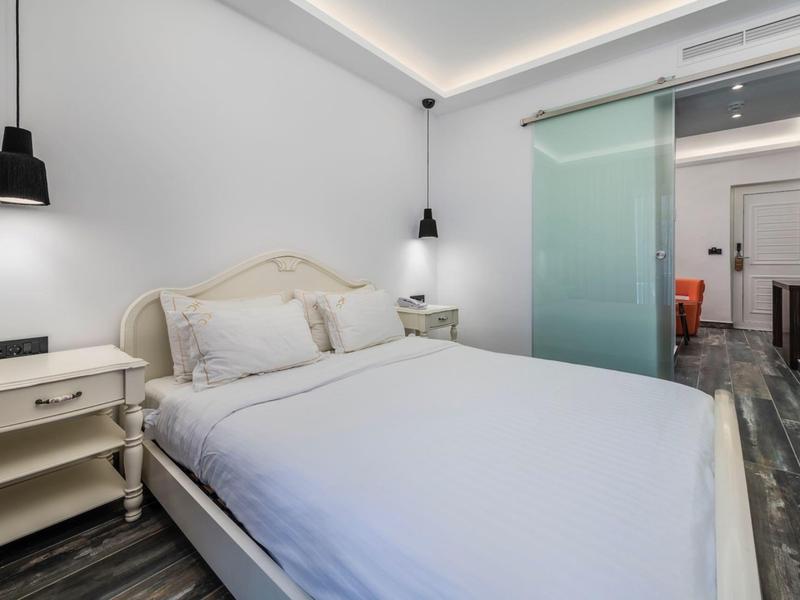 Bedroom with double bed, white walls, two nightstands, and modern pendant lights.