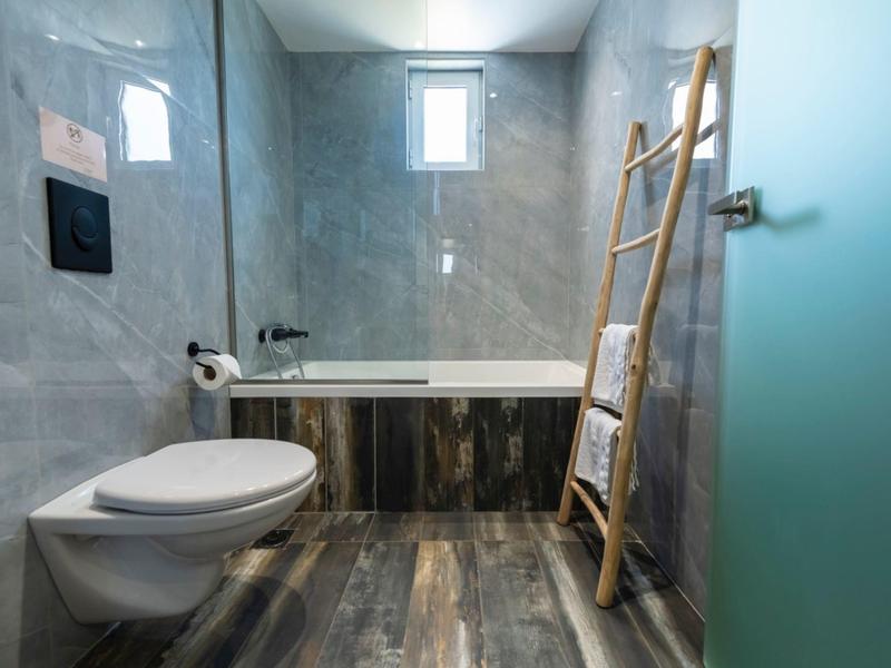 Modern bathroom with bathtub, toilet, and ladder towel rack.