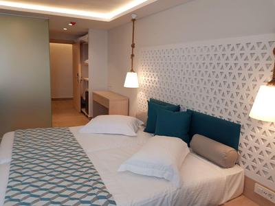 Modern hotelkamer met tweepersoonsbed, decoratieve kussens en zachte verlichting.