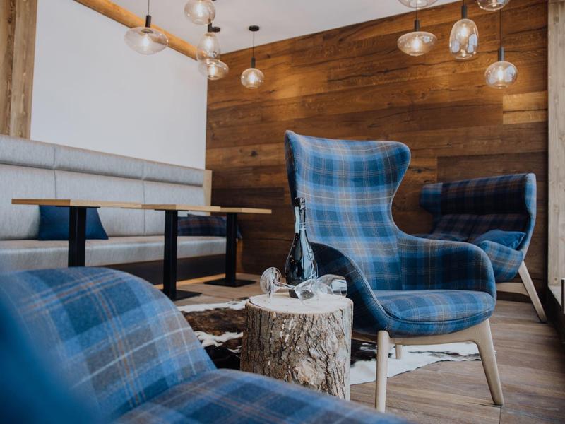 Gemütliche Sitzecke mit blauen Sesseln, Holztisch und Holzverkleidung an der Wand.