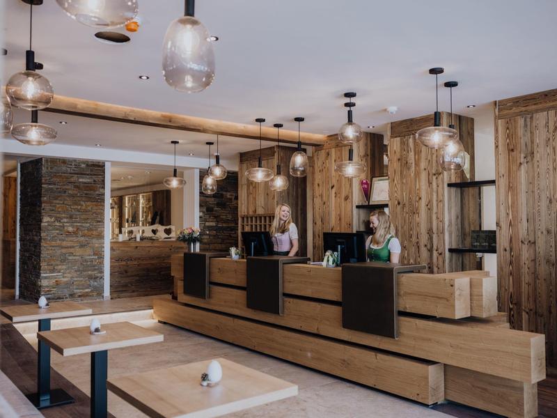 Modernes Café mit Holztheke, Pendelleuchten, hellen Holzmöbeln und freundlichem Personal.