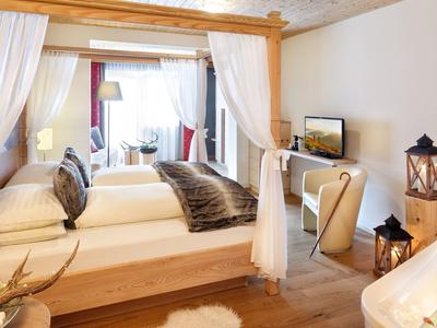 Cozy hotel room with wooden canopy bed, soft lighting, and modern decor in warm tones.