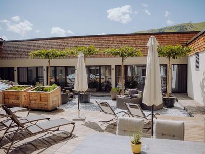 Dachterrasse mit Liegestühlen, Sonnenschirmen und Pflanzen in einem Hotel.