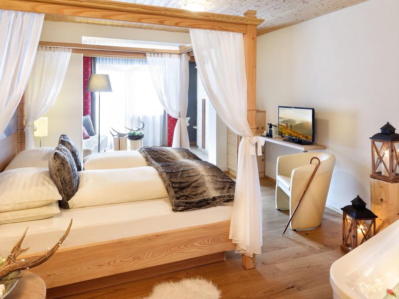 Cozy hotel room with wooden canopy bed, soft lighting, and modern decor in warm tones.