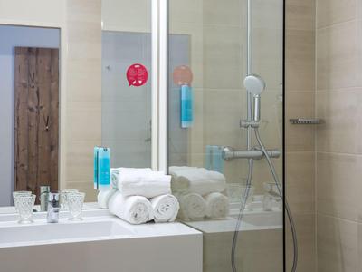 Modernes Badezimmer mit Glasdusche, Handtüchern und Toilettenartikeln.