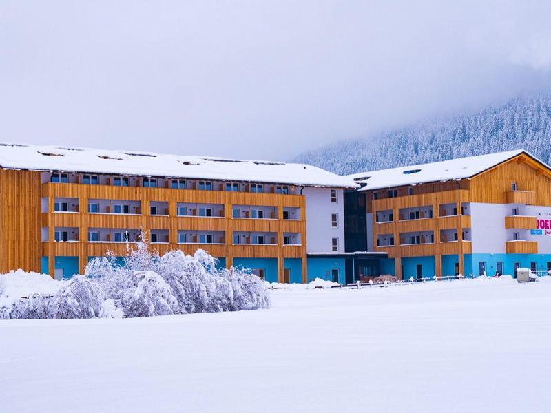 Großes Hotelgebäude umgeben von Schnee in einer winterlichen Berglandschaft.