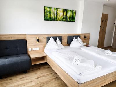 Habitación de hotel moderna con cama doble, sofá y suelo de madera.