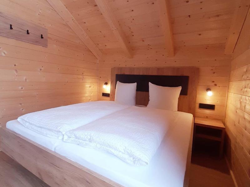 Cozy bedroom with wooden walls and ceiling, and a large bed with white bedding.