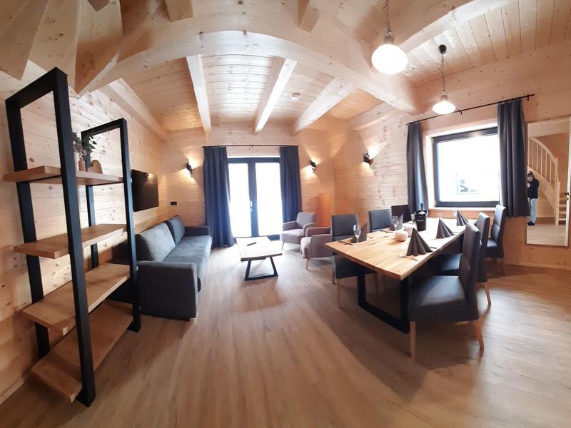 Bright living area with wooden walls, modern furniture, and large windows in a vacation home.