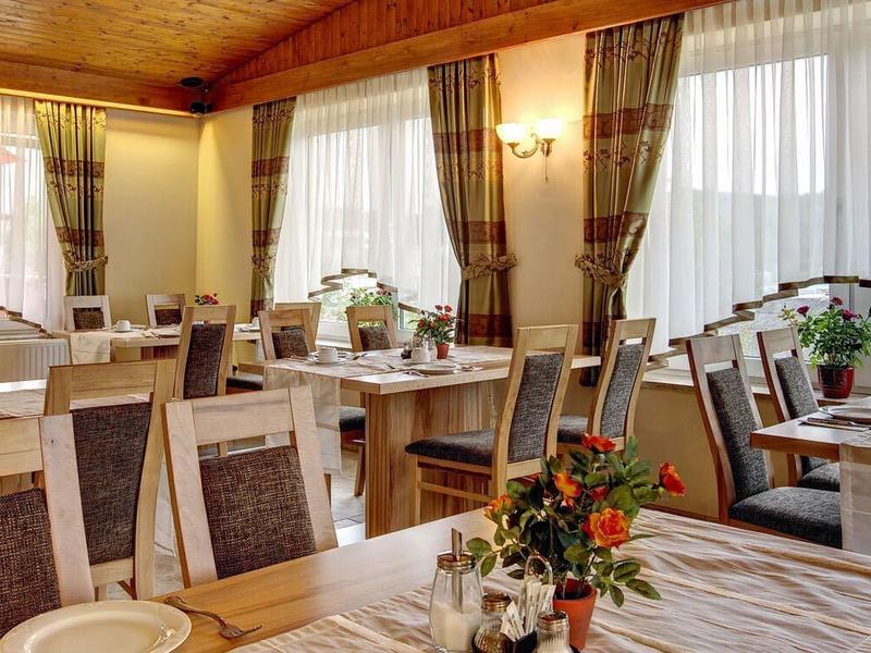 Heller, gemütlicher Speisesaal mit Holzmöbeln, gedeckten Tischen und großen Fenstern