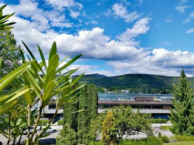 Blick auf Hotelgebäude mit Bäumen und Bergen im Hintergrund unter blauem Himmel mit Wolken