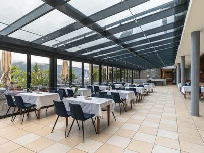 Heller, moderner Wintergarten mit Tischen und Stühlen, ideal für Hotelgastronomie.