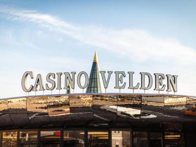 Eingang eines Casinos mit reflektierendem Dach und der Aufschrift 'Casino Velden'.