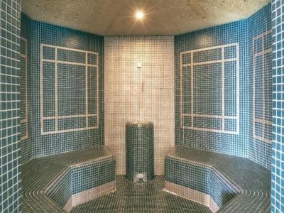 Moderner Dampfbadraum mit grauen Mosaikfliesen und integrierter Sitzbank.