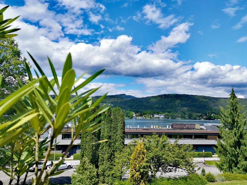 Blick auf Hotelgebäude mit Bäumen und Bergen im Hintergrund unter blauem Himmel mit Wolken