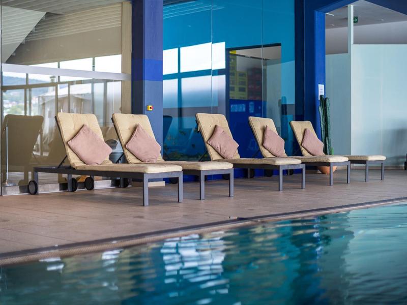 Poolbereich mit Liegestühlen und Kissen in einem modernen Innenbereich.