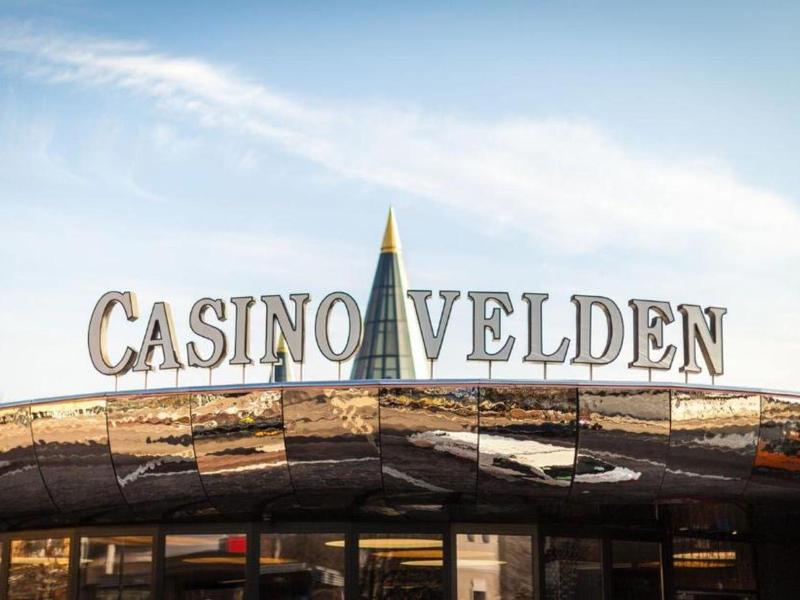 Eingang eines Casinos mit reflektierendem Dach und der Aufschrift 'Casino Velden'.