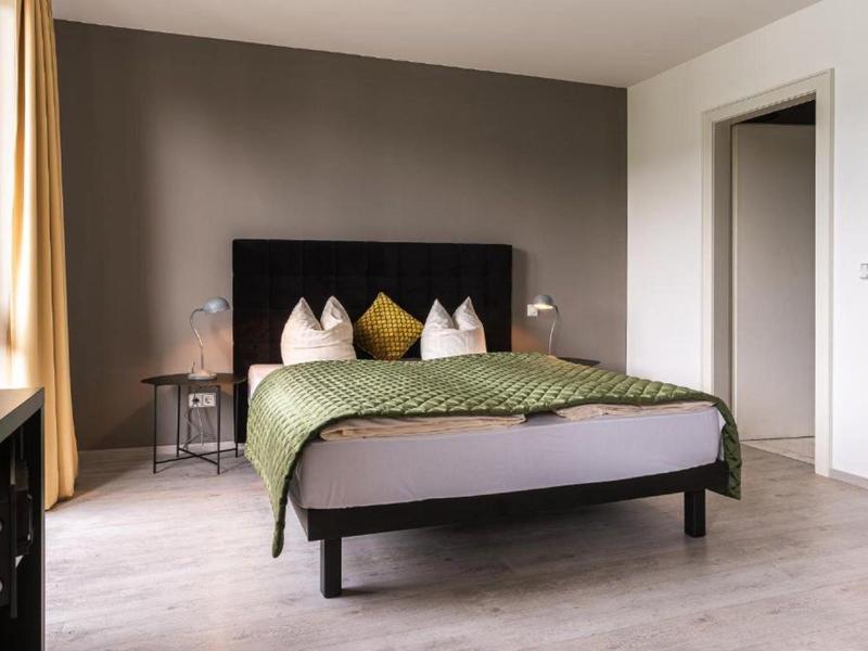 Modernes Schlafzimmer mit großem Bett, dekorativen Kissen und minimalistischen Nachttischen.