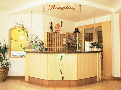 Helle Hotelrezeption mit Holzempfangstresen, Pflanze und Dekoration im Hintergrund.