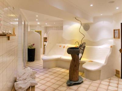 Modern spa room with illuminated whirlpool bathtub and wooden decor