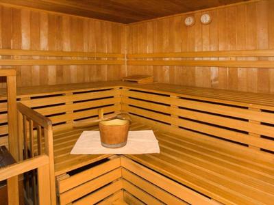 Wooden sauna with multi-tiered benches and a wooden bucket on a towel in the corner