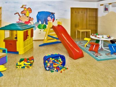 Colorful children's playroom with slide, playhouse, and toys in a bright room.