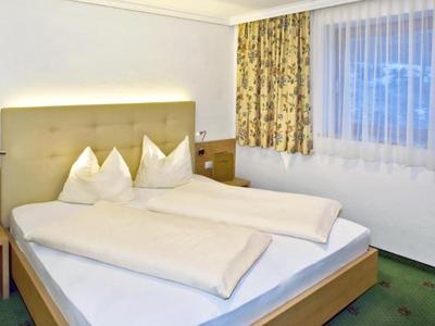 Cozy hotel room with a double bed, curtains, and carpeted floor.