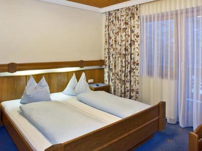 Cozy hotel room with two single beds, wooden furniture, and large windows with curtains.