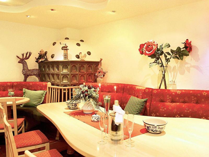 Cozy seating area with red upholstered sofa, wooden table, and decorative elements like roses and deer figure.